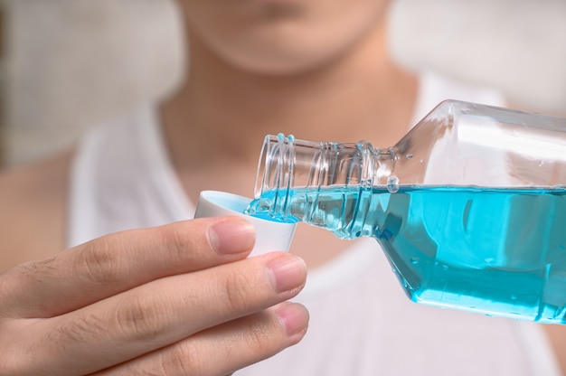 Hand of man Pouring Bottle Of Mouthwash Into Cap.