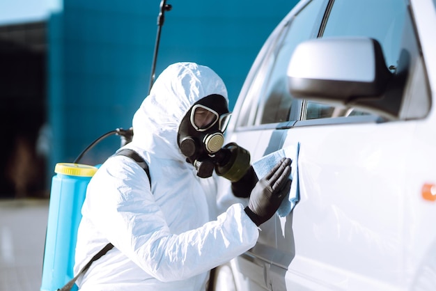 Hand of Man in protective suit washing and disinfection handles of a car