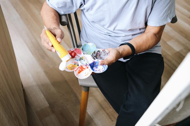 Hand of man squeezes the oil paint from the tube into the palette