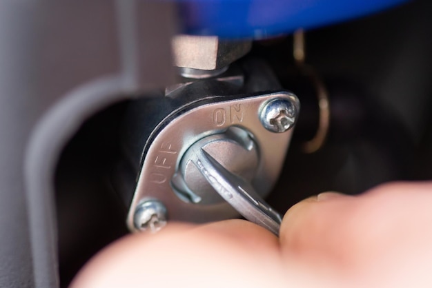 Hand of a man turning on a fuel switch of generator to produce electricity close up