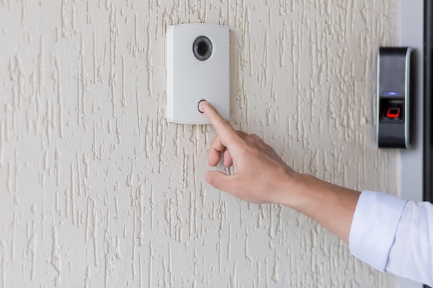 Photo hand of a man in a white shirt pressing the button of a door