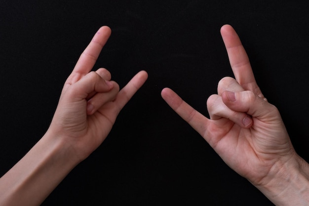 Photo hand of a man and a woman making the sign of the horns on a black background