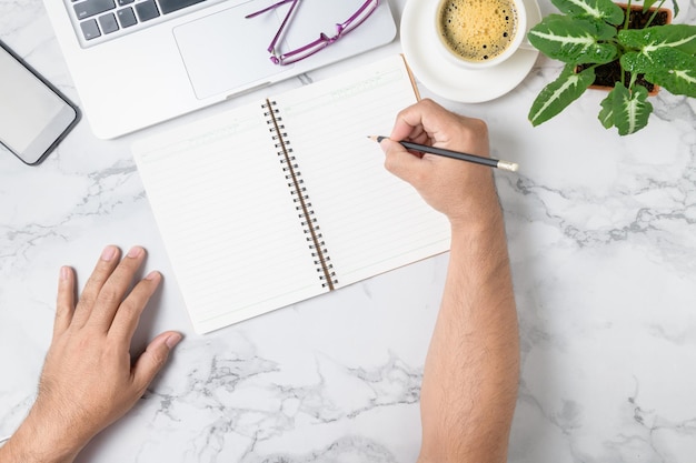 Photo hand man writing on blank notebook with laptop and coffee