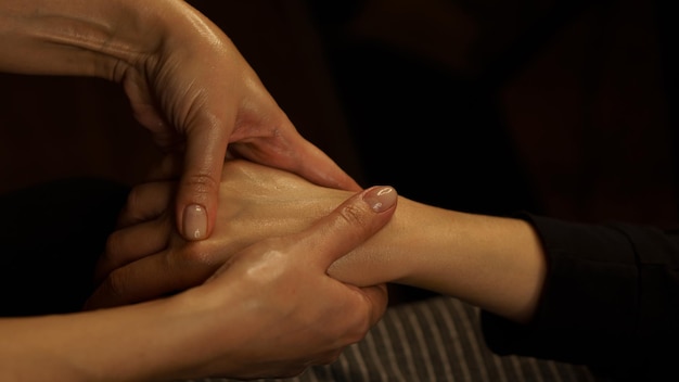 hand massage with body oil in a massage parlor closeup on a dark background