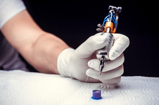 Hand of a master of the art of tattooing and a tattoo machine