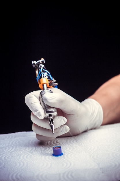 Hand of a master of the art of tattooing with a tattoo gun