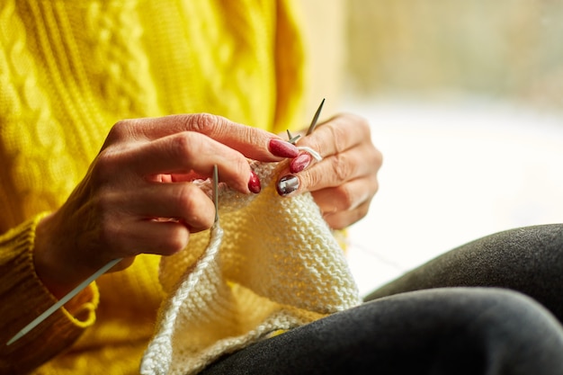 Hand of Mature female sitting on the windowsill and knitting