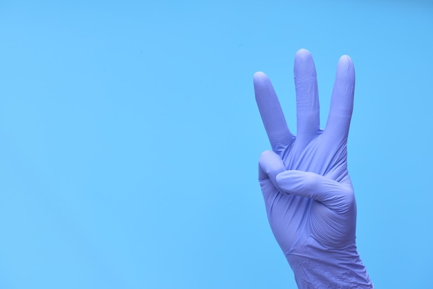 A hand in medical blue gloves shows a countdown of time or the number of drugs