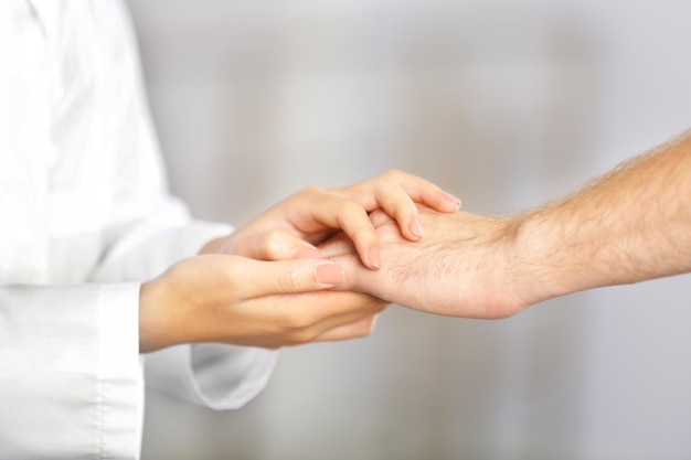 Hand of medical doctor carefully holding patient's hands