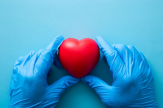 Photo hand in medical glove hold red heart sign health care charity donation concept