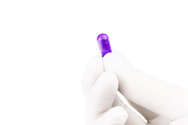 Hand in medical glove holding proton purple color organic med capsule isolated on white background closeup