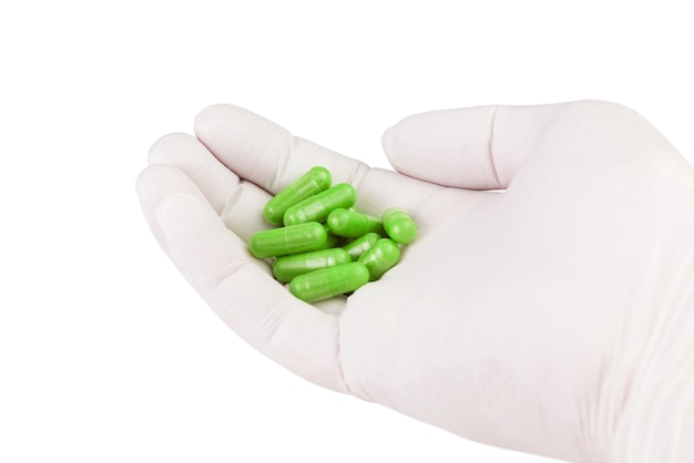 Hand in medical glove holding ufo green color organic med capsules isolated on white background closeup