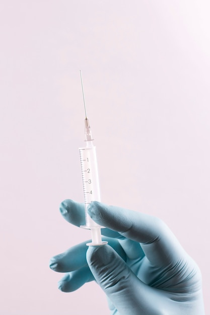 A hand in a medical glove holds a syringe.