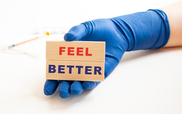 A hand in a medical glove holds wooden cubes with the inscription.