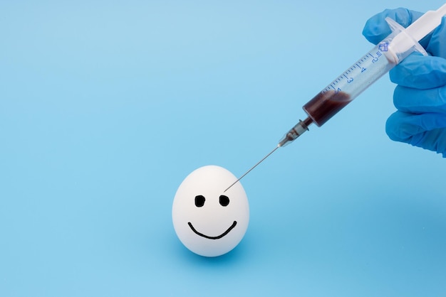 A hand in a medical glove injects an antibiotic into an egg closeup Vaccination of pregnant women against covid19