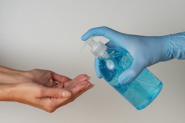 Photo hand in medical glove with hand sanitizer in a bottle on white.