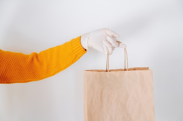 Hand in a medical glove with a paper delivery bag