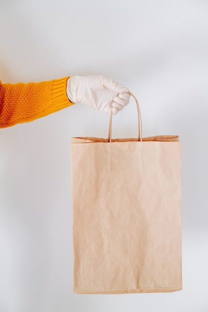Hand in a medical glove with a paper delivery bag
