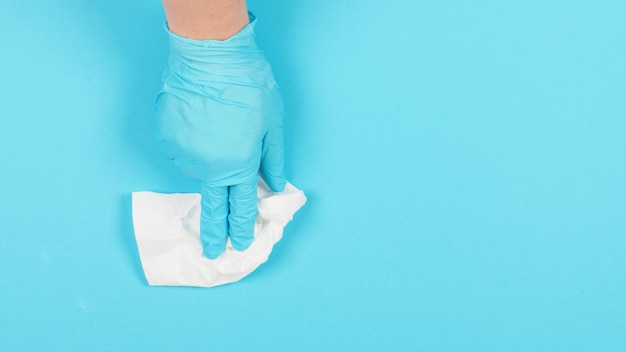 Hand medische handschoen dragen en tissuepapier afvegen op blauwe achtergrond studio foto