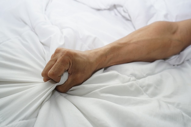 Hand of men pulling white sheets in ecstasy, orgasm.