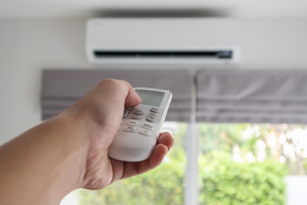 Hand met afstandsbediening gericht op airconditioner