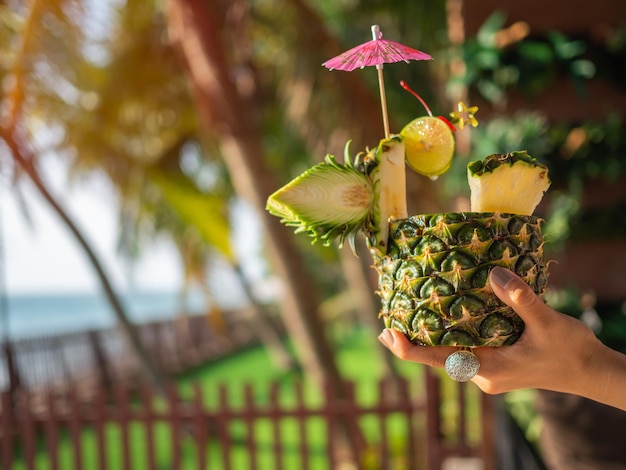 Hand met ananassapcocktail in de buurt van het strand in de zomer