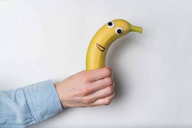 Hand met banaan met grappig gezicht. snel snackconcept. Veganistisch.