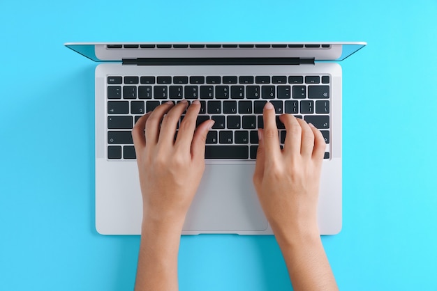 Foto hand met behulp van laptopcomputer op blauwe achtergrond bovenaanzicht