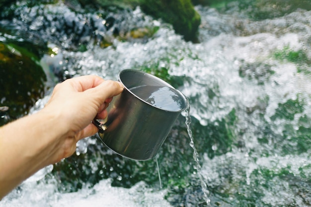 Hand met beker met zuiver waterval drinkwater