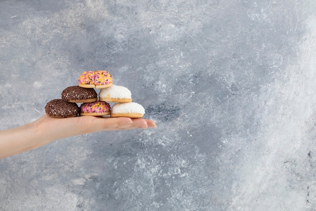 Hand met bos van bladerdeeg cookies op marmeren oppervlak.