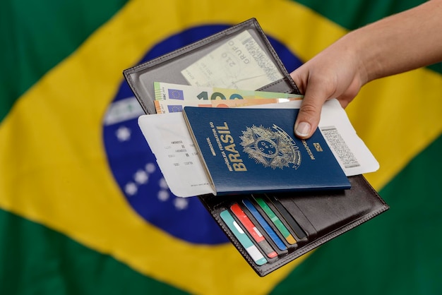 Hand met Braziliaans paspoort met Braziliaanse vlag op de onscherpe achtergrond