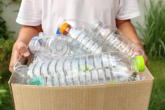 Hand met bruine recycle vuilnisbak met plastic flessen