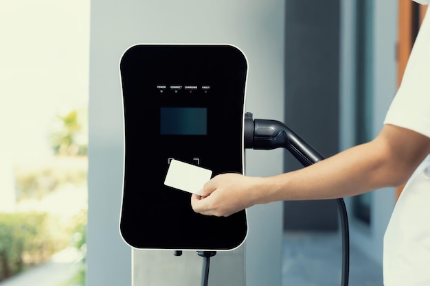 Hand met creditcard en laadstation betalen voor progressieve EV-auto