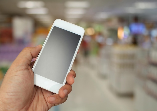 Hand met de smartphone op supermarkt in wazig voor achtergrond