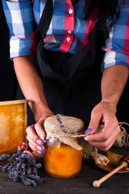 Hand met dipper plukken honing uit een pot met honing.