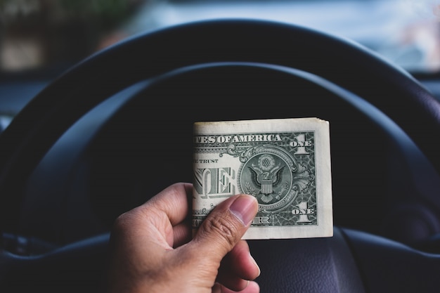 Hand met dollar geld in de auto