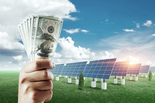 Hand met dollars op de achtergrond van zonnepanelen... Zonnepaneel kosten, zonne-energie bedrijf.