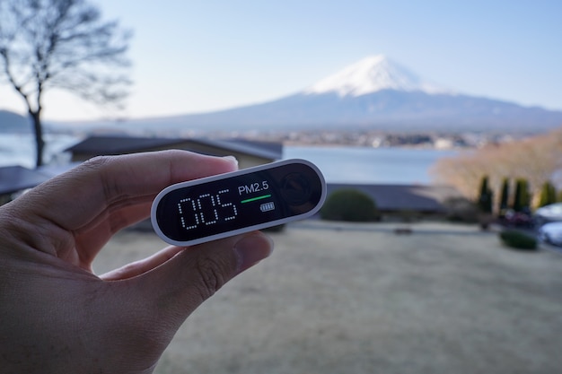 Hand met draagbare luchtkwaliteitsdetector met Mt. Fuji of Fuji-san bij Lake Kawaguchiko, Japan.