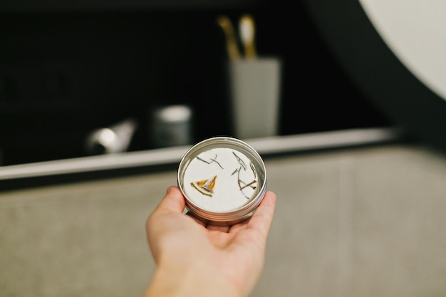 Hand met eco solide shampoo in metalen blik in moderne badkamer op achtergrond van stijlvolle zwarte plank met plastic vrije natuurlijke organische benodigdheden Zero waste concept Natuurlijke benodigdheden