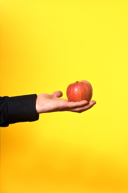 Foto hand met een appel op gele achtergrond