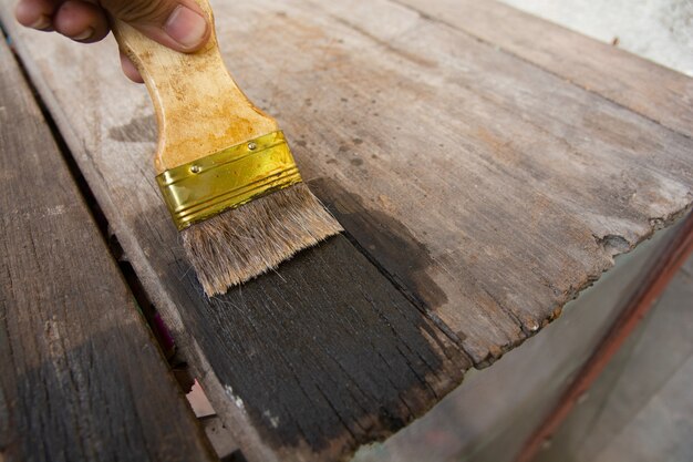 Hand met een borstel schilderij houten houten planken oppervlak met hout vlek