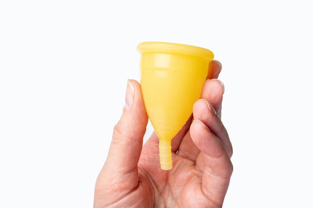 Hand met een gele menstruatiecup op een witte achtergrond Gezondheidsconcept voor vrouwen Eco-vriendelijk concept Geen afvalconcept