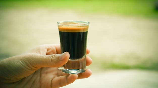 Hand met een glas espresso koffie