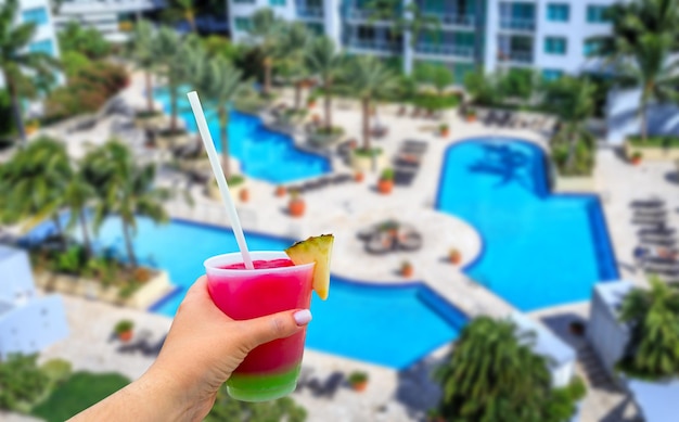 Hand met een glas met cocktail en stro en hotel met zwembad in antalya