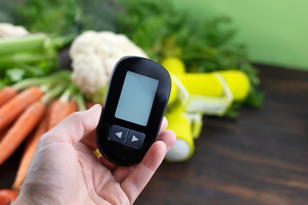 Hand met een glucosemeter tegen lage glycemische gezonde voeding op de achtergrond Diabetische voeding en gezond leven concept