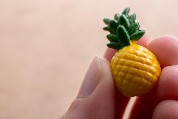 Hand met een kleine ananasminiatuur op een tentoongestelde achtergrond