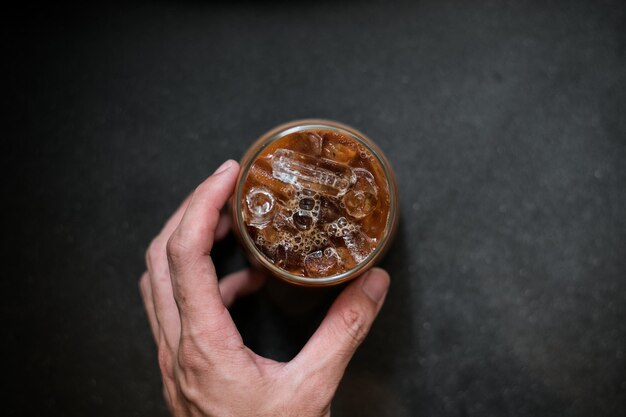 hand met een meeneem ijskoffie op zwarte tafel