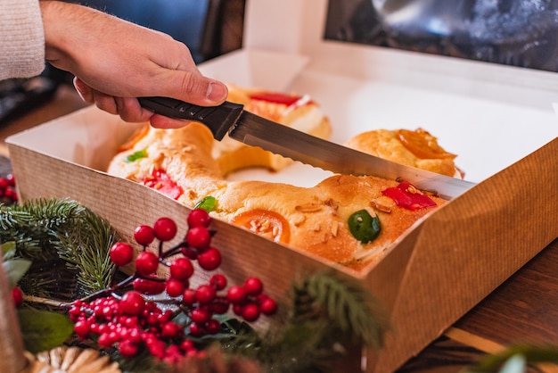 Hand met een mes snijden een traditioneel Spaans kerstdessert gemaakt met deeg, fruit en room