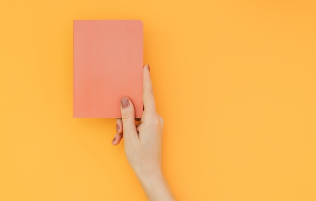 Hand met een rode Kladblok op het oranje oppervlak