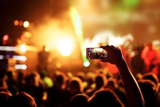 Hand met een smartphone neemt live muziekfestival live concertshow op het podium op